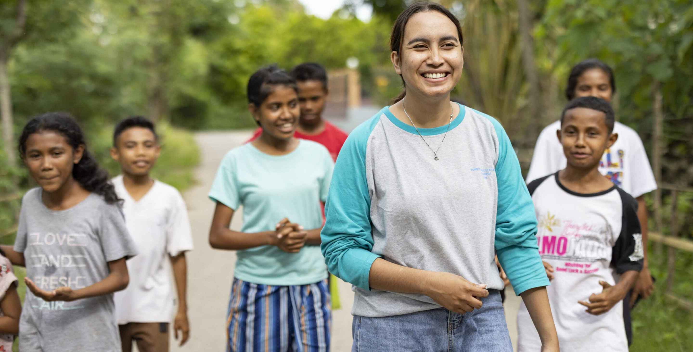 young woman smiling and leading a group of kids, walking together