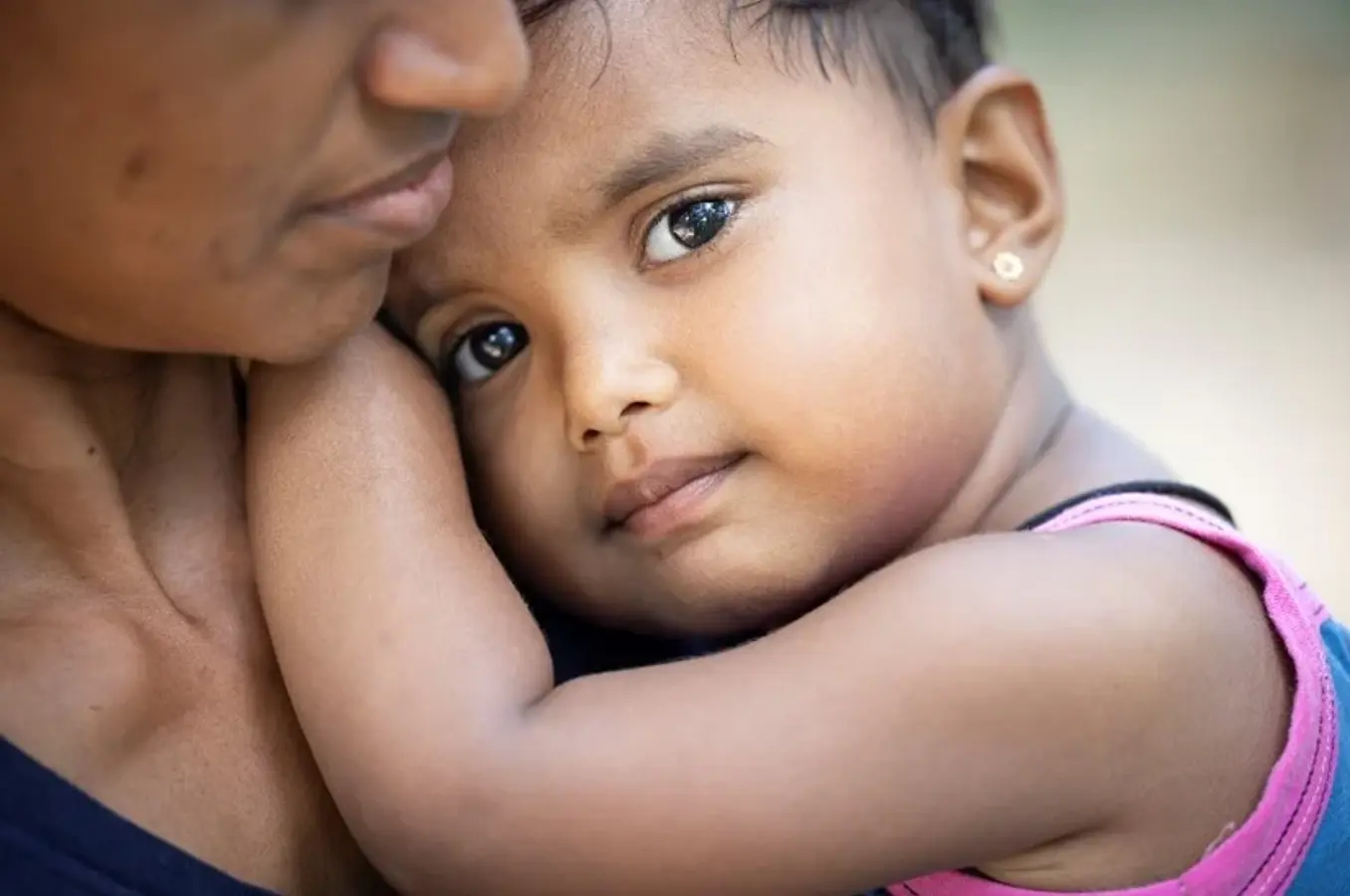 A mother holds a child in their arms.