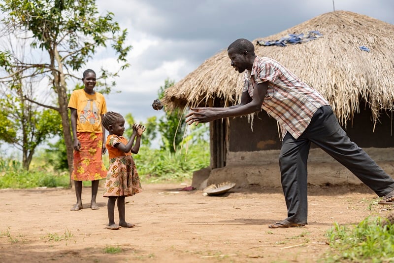 A dad throws his daughter a homemade ball in Uganda.