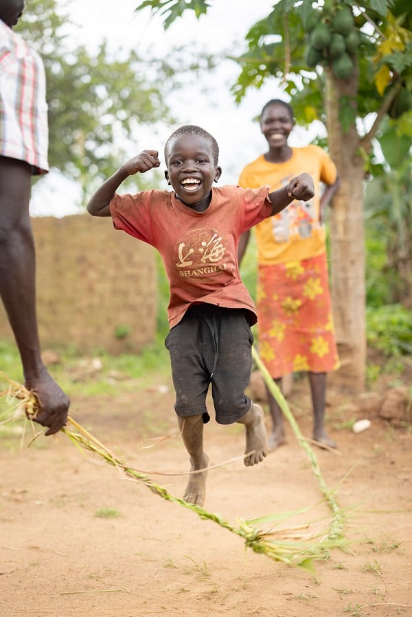 A boy jumps rope in Uganda, smiling.