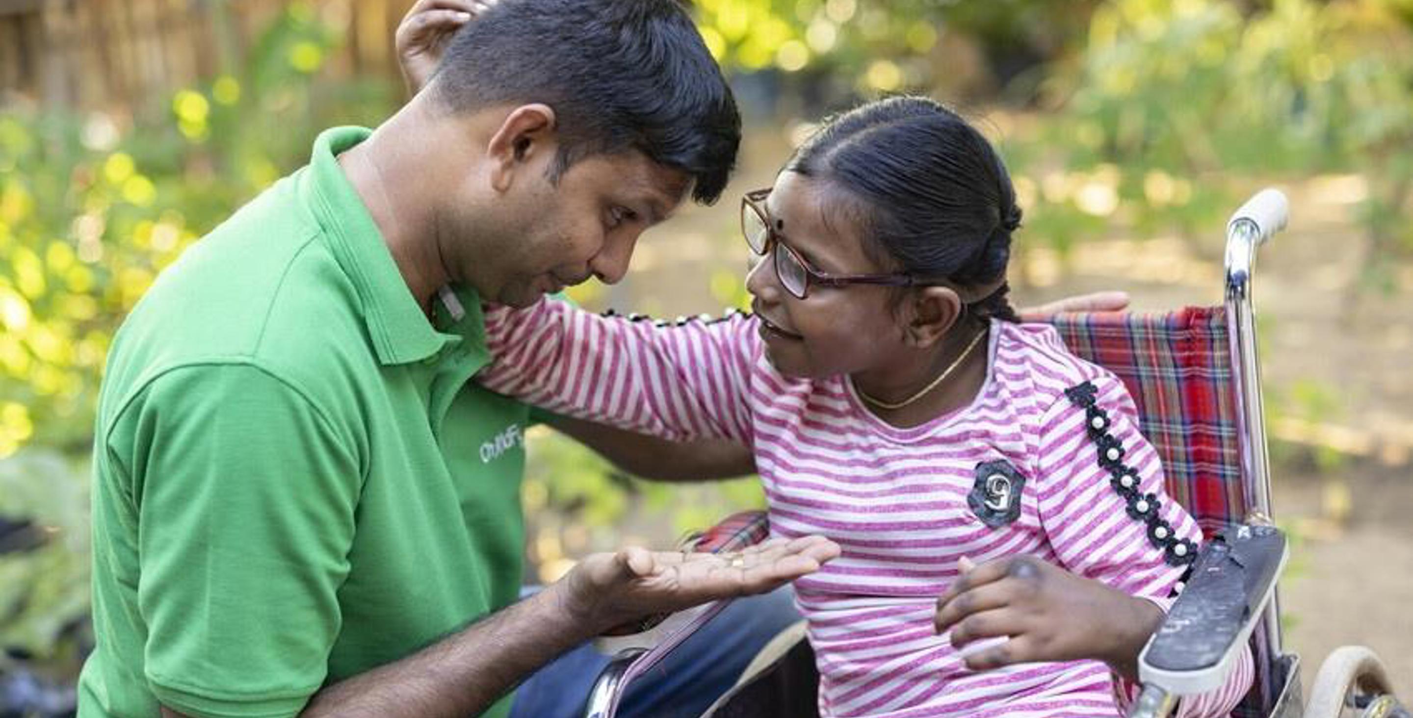 ChildFund staffer and a girl in a wheelchair in playful conversation