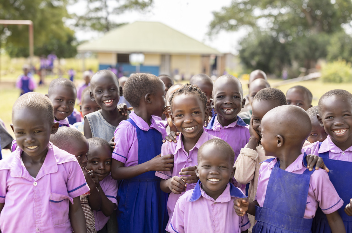 A group of children at an ECD center in Uganda smile at the camera.