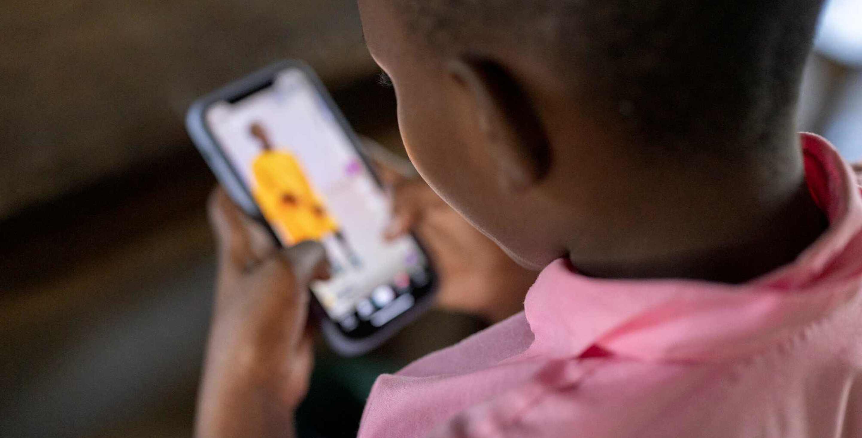 child viewing a smartphone, seen from behind