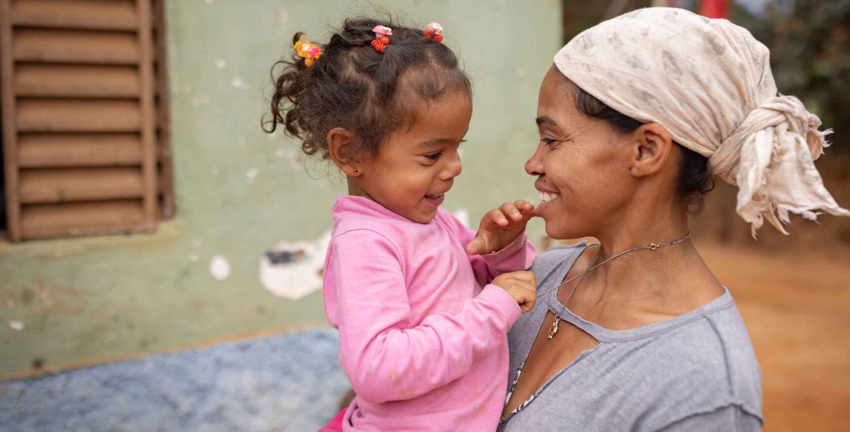 woman holding her daughter, both smiling, seen from side