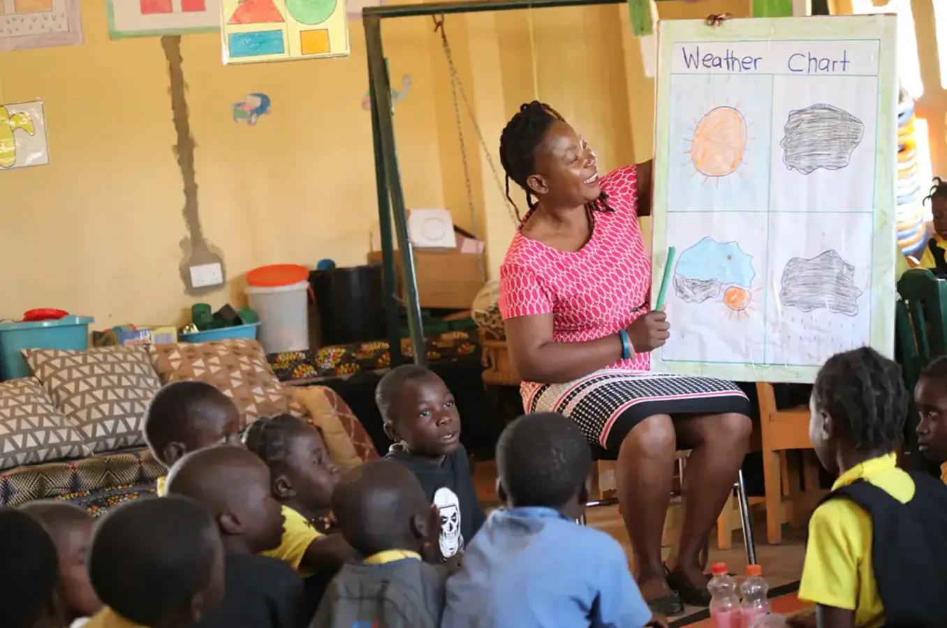 Teacher sits in front of the classroom teaching a lesson