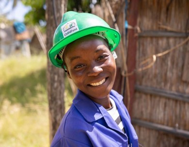Youth in hard hat smiles outside while taking part in vocational training program