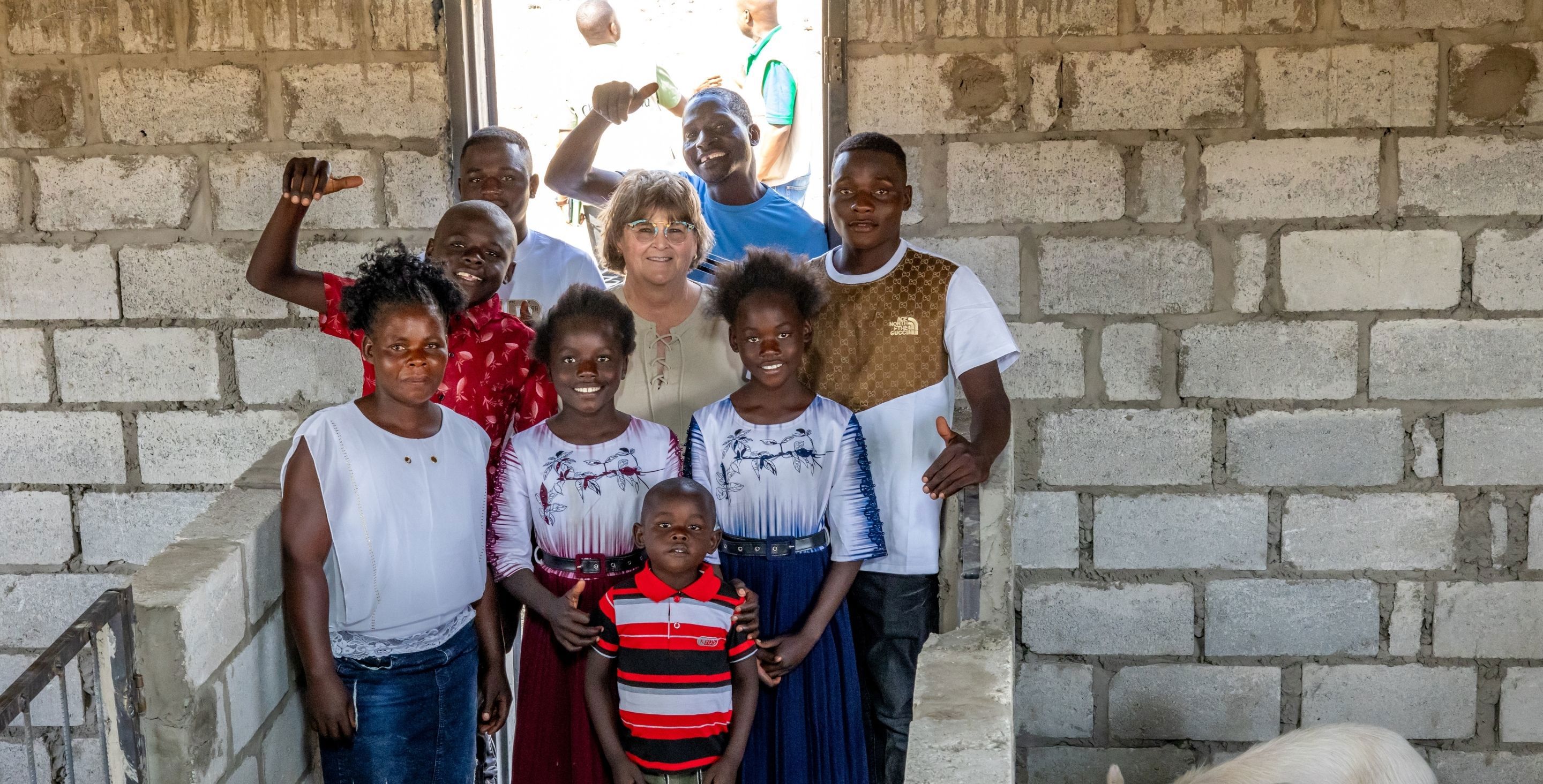 A sponsor stands together with a family in Zambia in the doorway of their home.