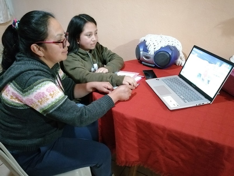 A young girl and her mom study at a computer in Ecuador.