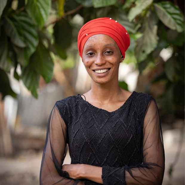 Penda, former sponsored child, smiles while wearing an orange head scarf.