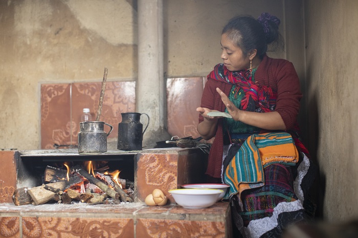 Mother makes tortillas over an open fire in Guatemala.