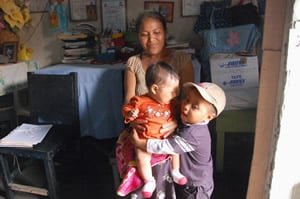 Woman holding infant girl, who is being hugged by little boy, standing. Woman holding infant girl, who is being hugged by little boy, standing.