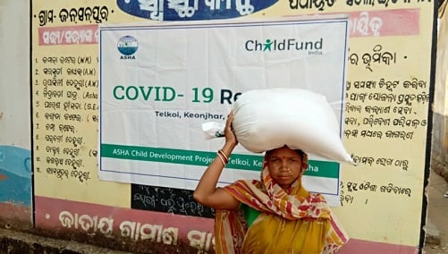 Woman standing outside holding bag of food in India.