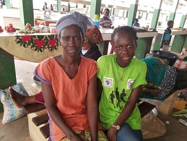 A mother and daughter sit at a market in The Gambia.