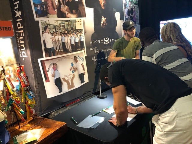 Man stands at ChildFund table signing up to sponsor a child.