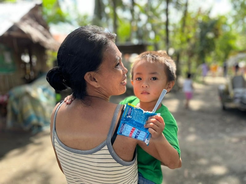 Mother in the Philippines holds a baby amid the damage after Typhoon Rai.