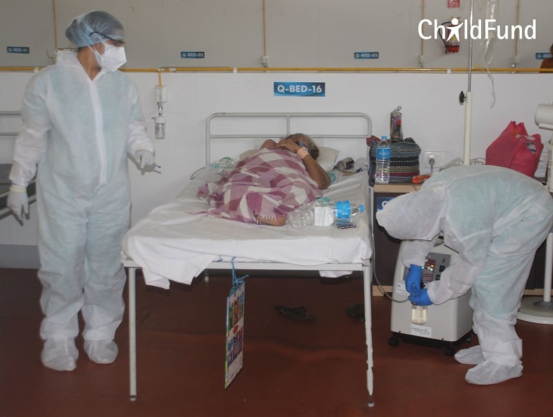 Health care workers in full personal protective gear care for a woman sick with COVID-19.