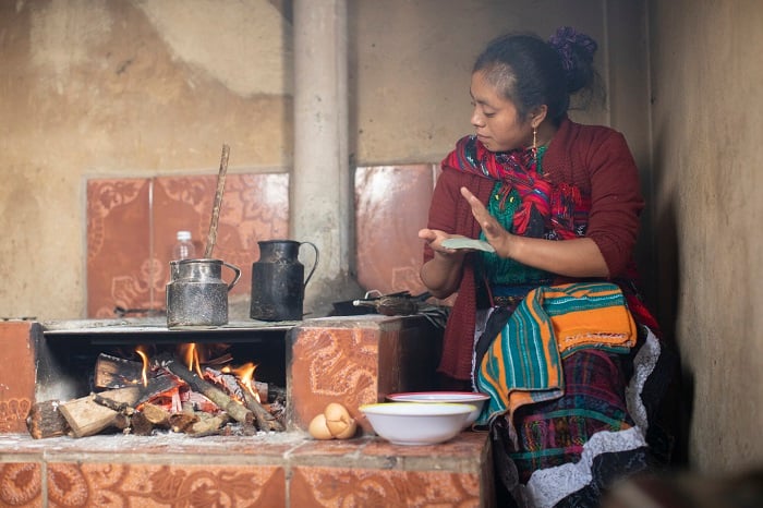 Mother makes tortillas over an open fire in Guatemala.