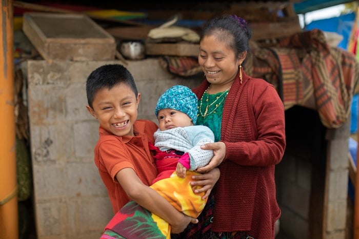 Family stands together, smiling, in Guatemala.
