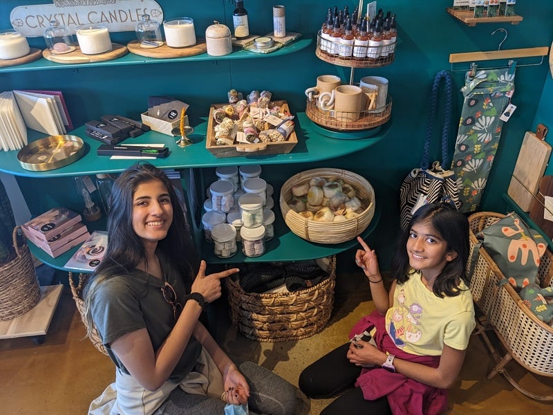 Sponsor Two young girls smile in front of a shelf of handmade goods