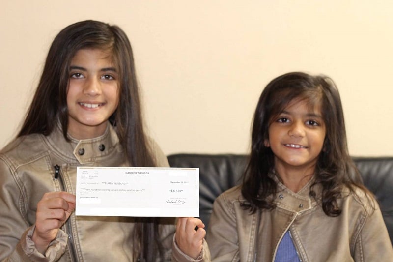 Kaylapageant Two young girls hold up a cashier's check, smiling