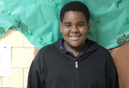 A young boy smiles at the camera.