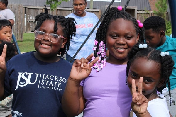 Three children in the U.S. smile up close in front of the camera.
