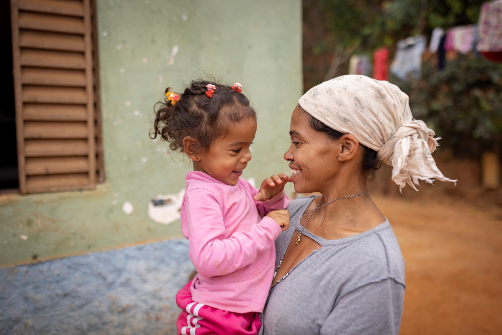 Mother in Brazil holds young girl in her arms, smiling.