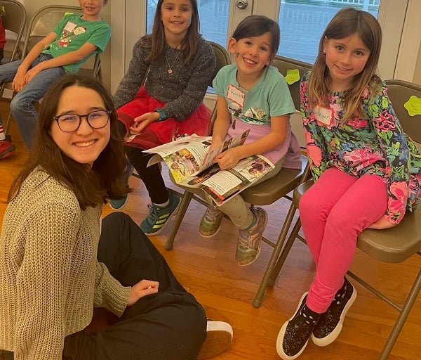 A group of students sit with copies of ChildFund's Real Gifts Catalog, smiling at the camera.
