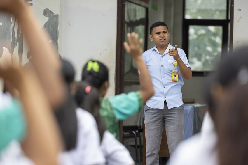 Well-dressed man speaks to a group of students at a school in Indonesia.