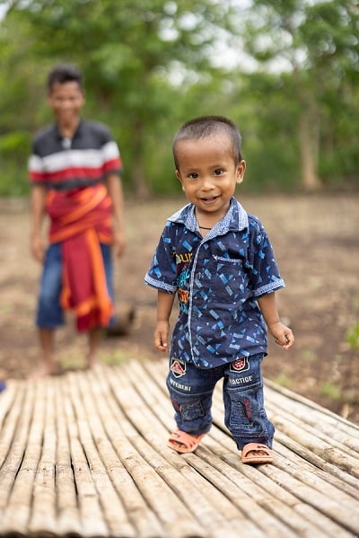 2 year old boy in Indonesia smiles at camera.