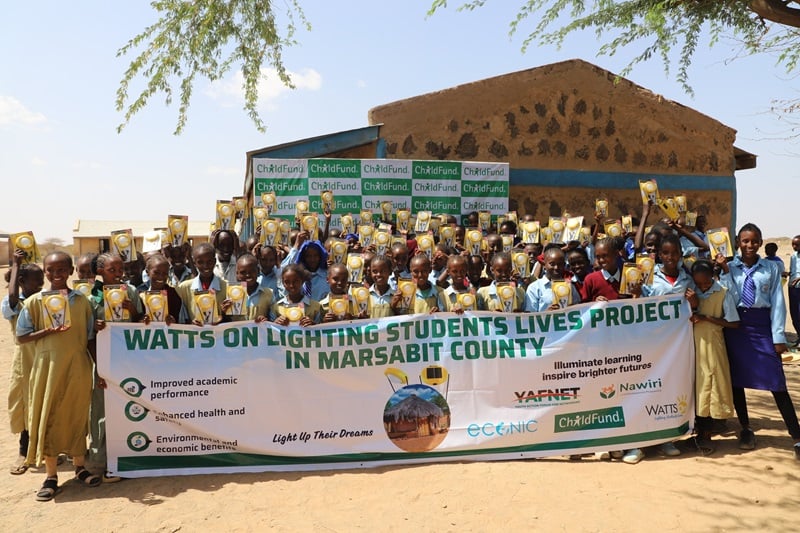 Children in Kenya smile as they hold up a banner with the project name