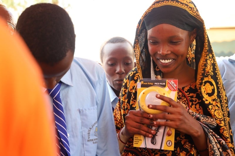 A woman smiles as she holds a solar lamp