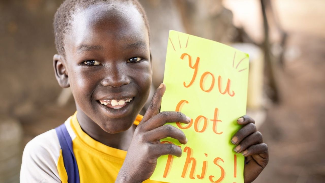happy young boy holds card with a message of encouragement
