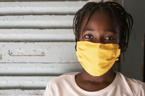 Girl in Senegal wears mask, looking at camera.